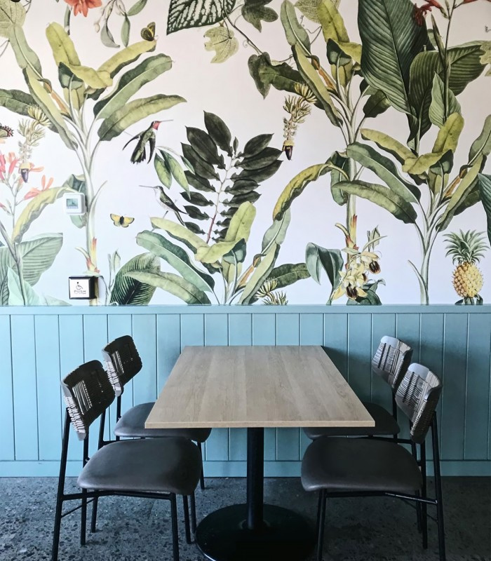 Tapeta Tropicana w jadalni – aranżacja stołu i krzeseł na tle roślinnego wzoru